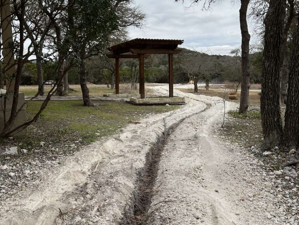 A cleared dirt road with a culvert dug gazebo in the background.